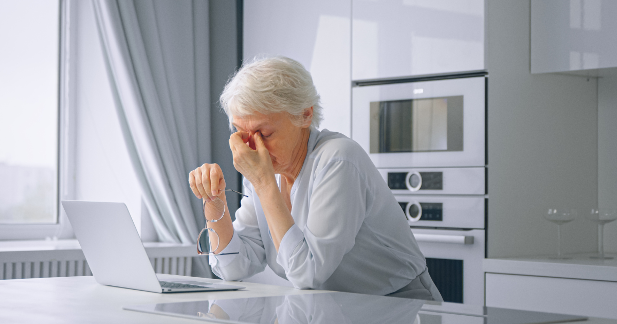 Older woman experiencing stress while reviewing finances on a laptop, illustrating the need for a financial planner during major life transitions