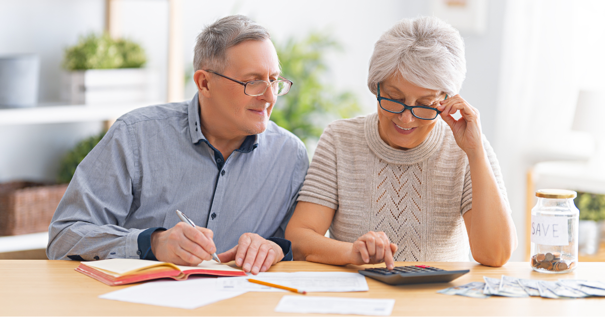 Mature couple reviewing documents together at a kitchen table while working on their long term financial planning.