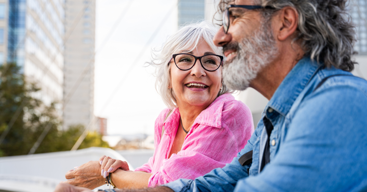 Happy retired couple smiling together outdoors, representing intentional retirement lifestyle planning and updated retirement goals.