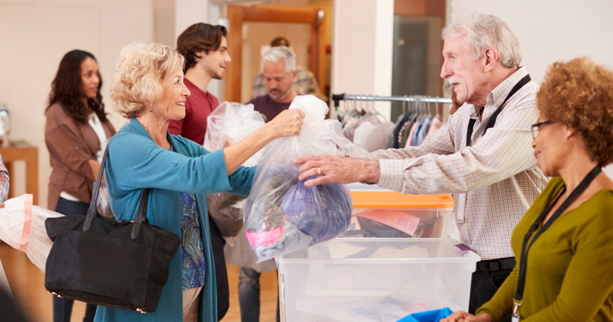 Senior volunteering in action as a retired couple hands over donated clothing at a charity drop-off.