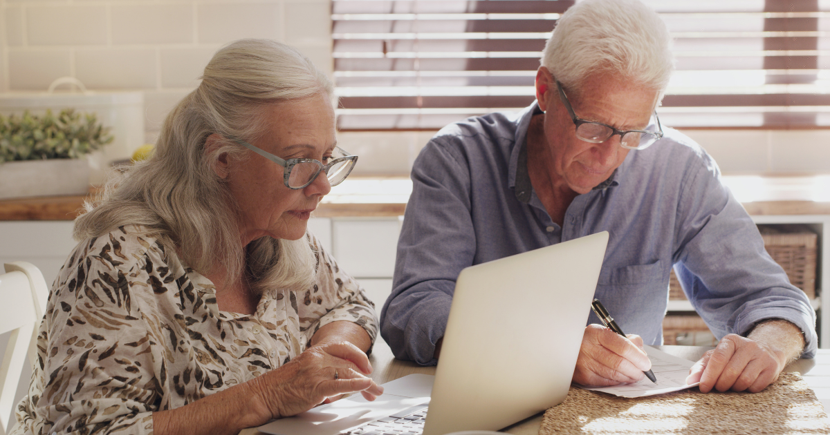 Retired couple reviewing Medicare Open Enrollment options together on a laptop at their kitchen table
