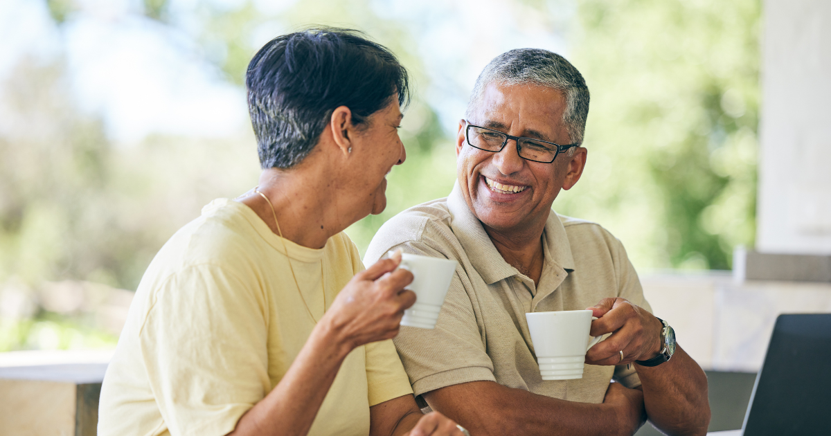 A mature couple smiling while using a laptop to discuss their retirement planning strategy and financial goals.